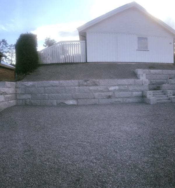 Steinlagt mur på en tomt foran et hvitt hus